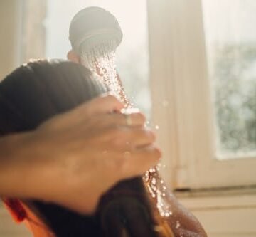 woman-washing-hair-with Does Rinsing Your Hair With Cold Water Actually Do Anything?