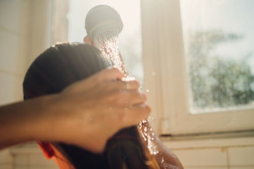 woman-washing-hair-with Does Rinsing Your Hair With Cold Water Actually Do Anything?
