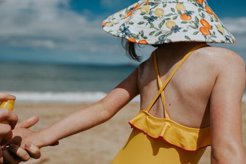 a-parent-holds-a Is Aerosol Sunscreen Safe For Kids? Here's What Dermatologists Use Instead