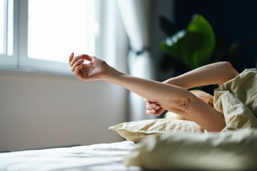 unrecognizable-woman-laying-in Waking Up With Your Hands Asleep Could Signal These Conditions